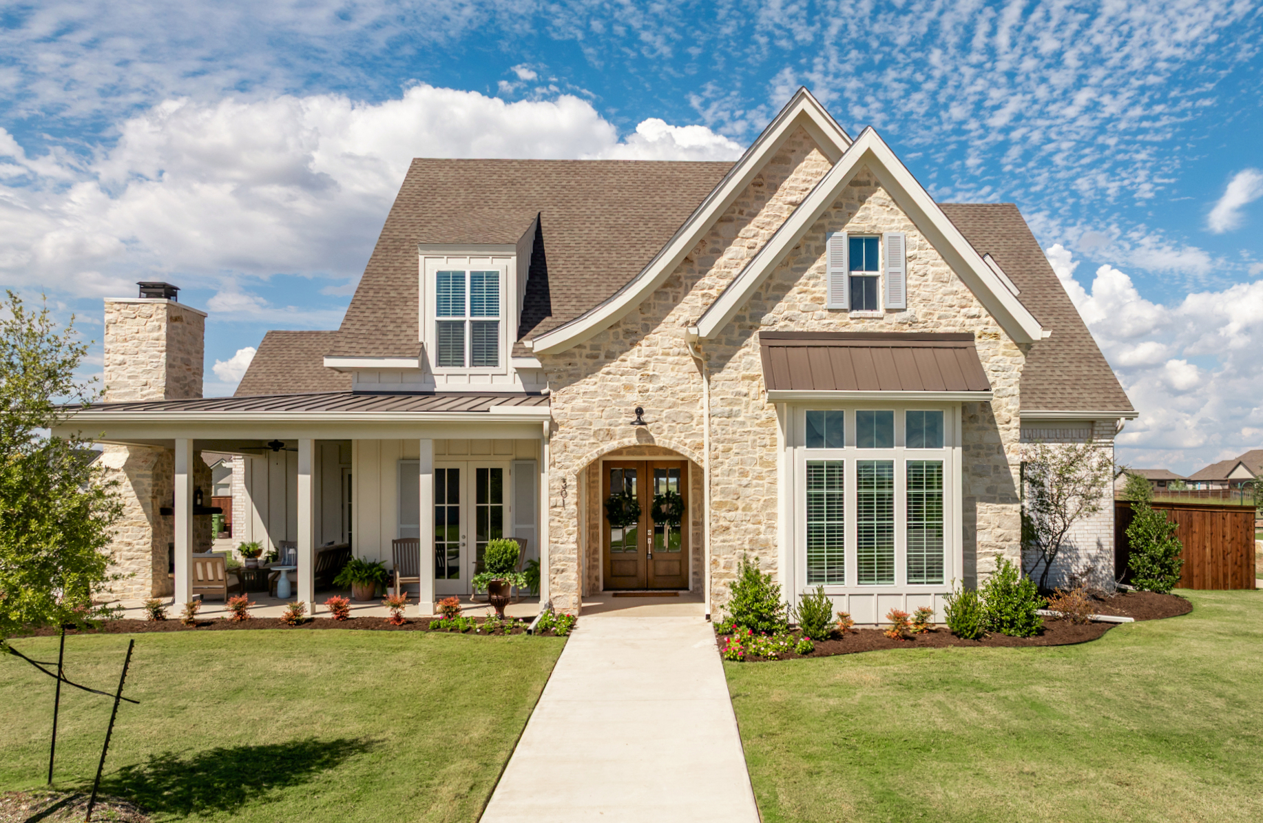 Sorrells & Co. stone home with a front porch and landscaped entry